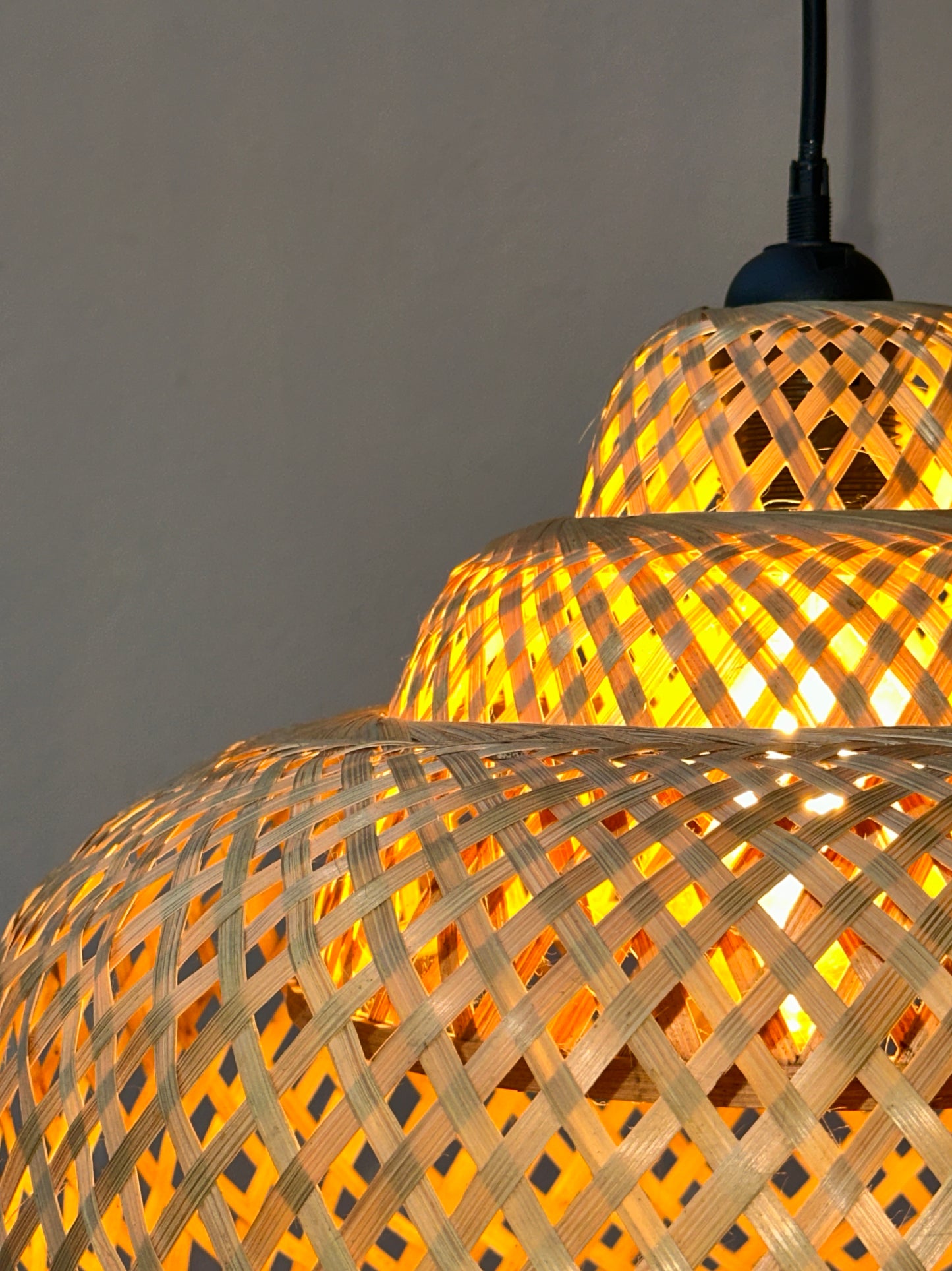 Woven bamboo lamp with warm glow on a gray background