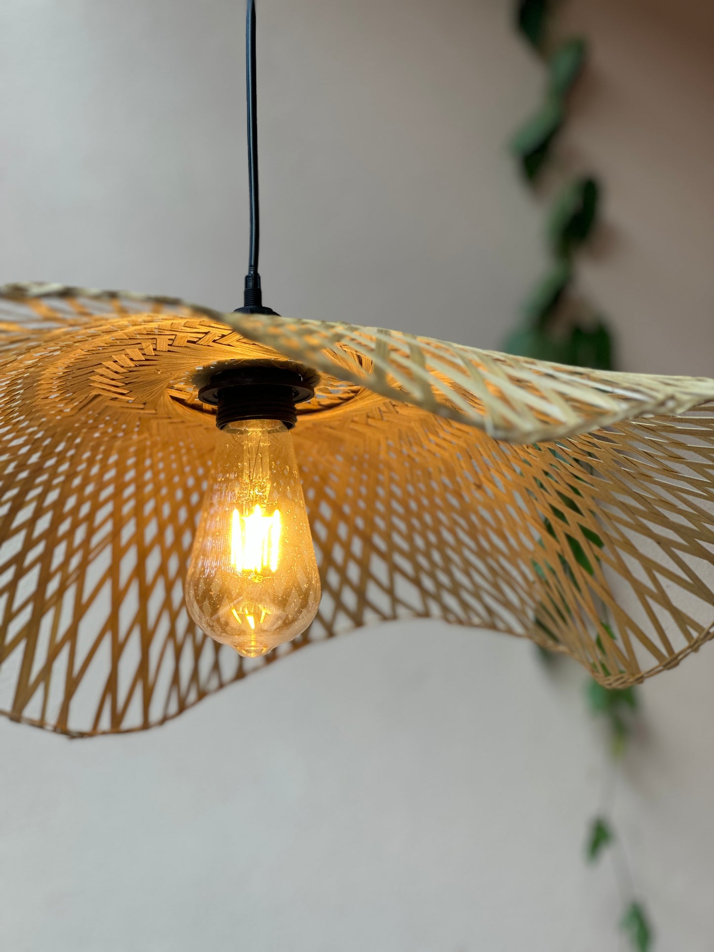 Decorative pendant light with a wicker shade and visible bulb against a neutral background