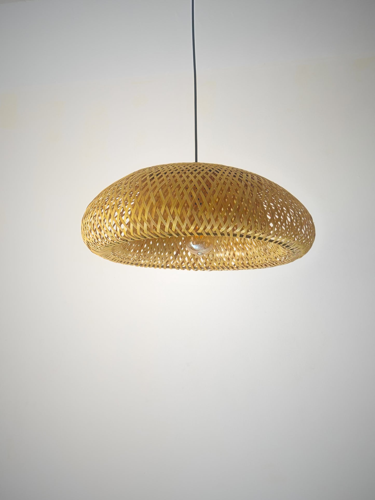 Woven pendant light fixture on a plain background