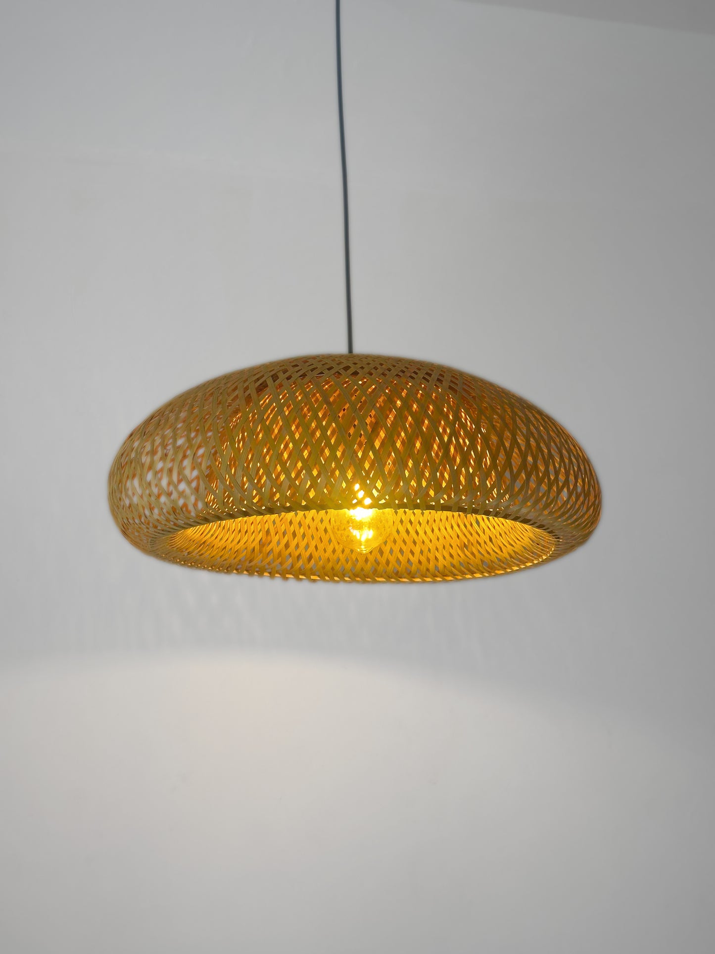 Woven pendant light with a gold finish on a plain background