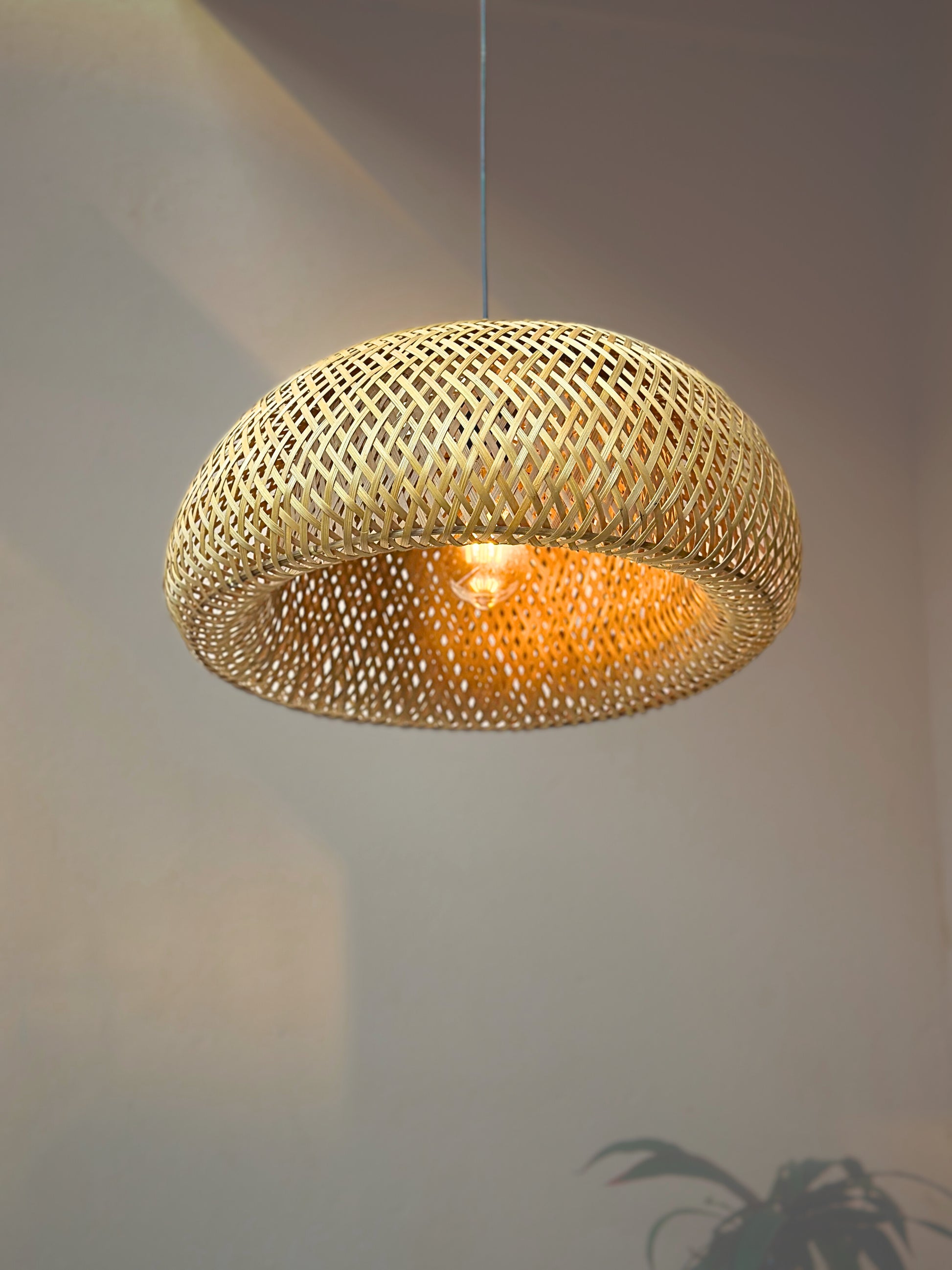 Woven pendant light hanging against a neutral background