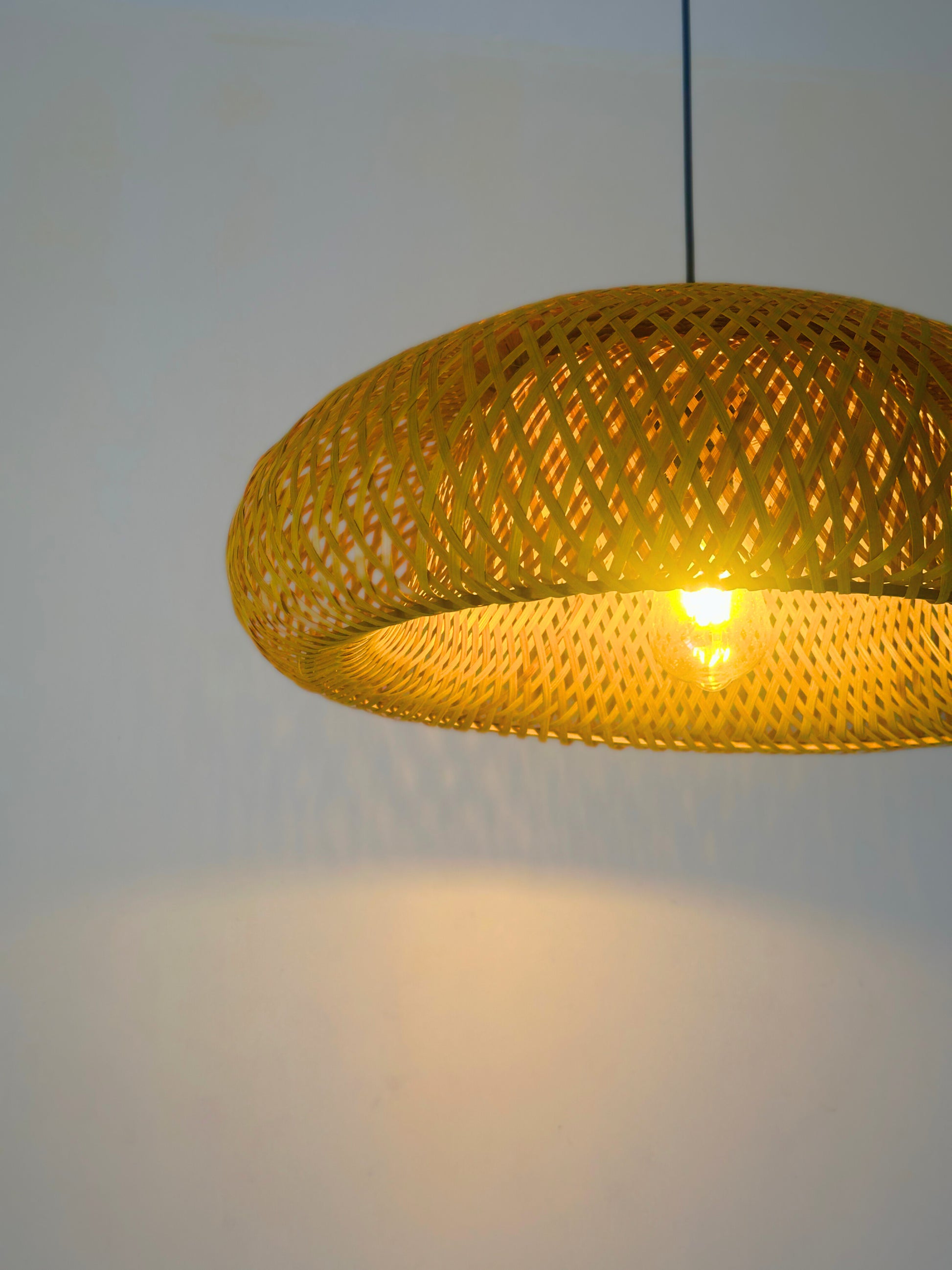 Yellow woven pendant light against a plain background