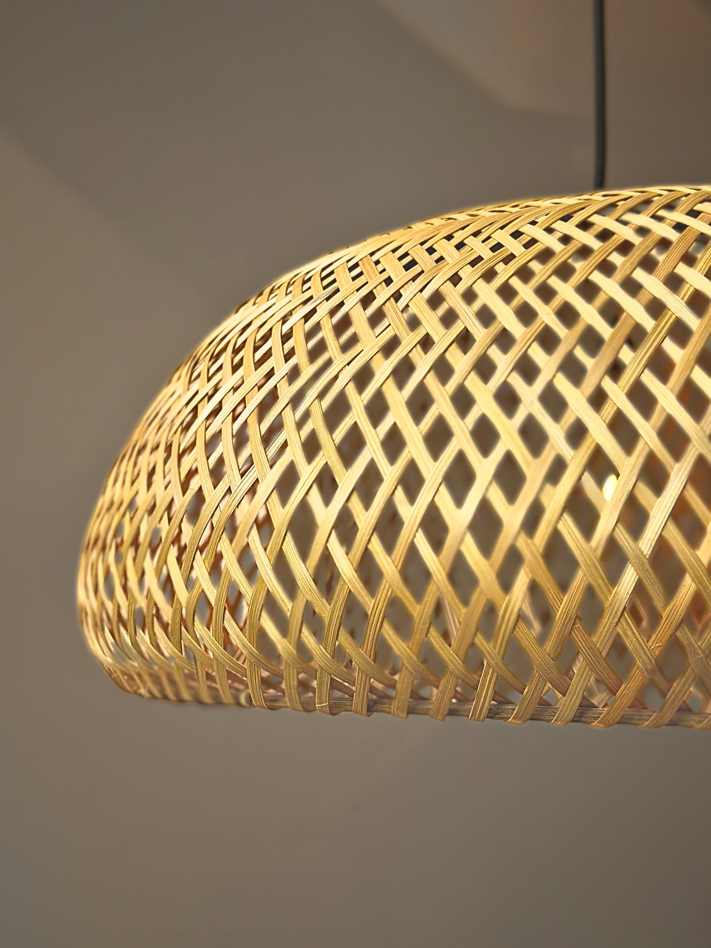 Woven rattan pendant light against a neutral background