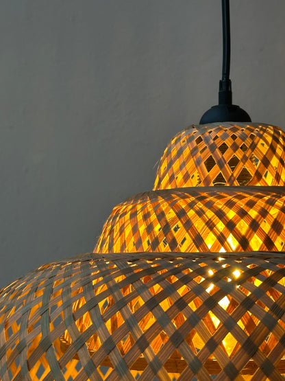 Woven bamboo lamp with warm glow on a plain background