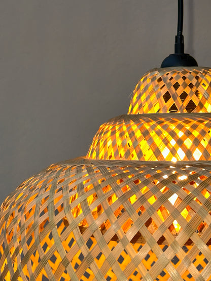 Woven bamboo lamp with warm glow on a gray background